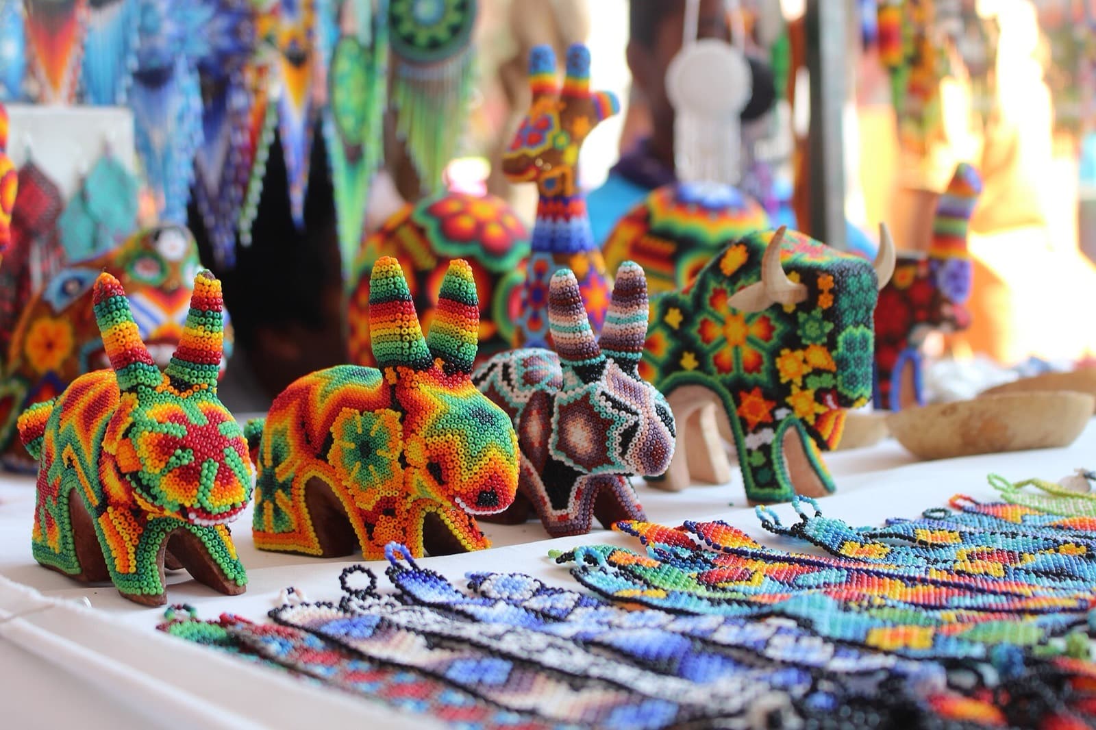 Figuras de animales cubiertas de chaquira multicolor y pulseras huicholas exhibidas sobre un mostrador